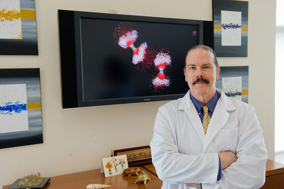 Massey researcher Paul Fisher standing in his lab coat with his arms crossed