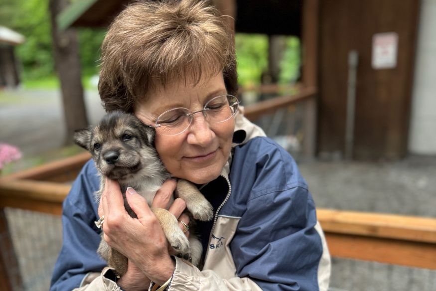 Woman holding and hugging a puppy to her face