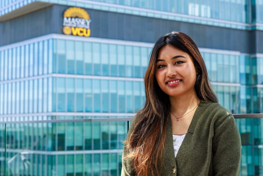 Portrait of young woman, Adina Shrestha, in front of building with Massey logo