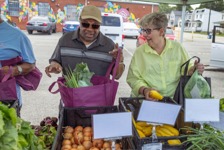 Massey patient Melissa Earley (right) talks with a fellow shopper at the Shalom Farms stand in Fulton Hill.