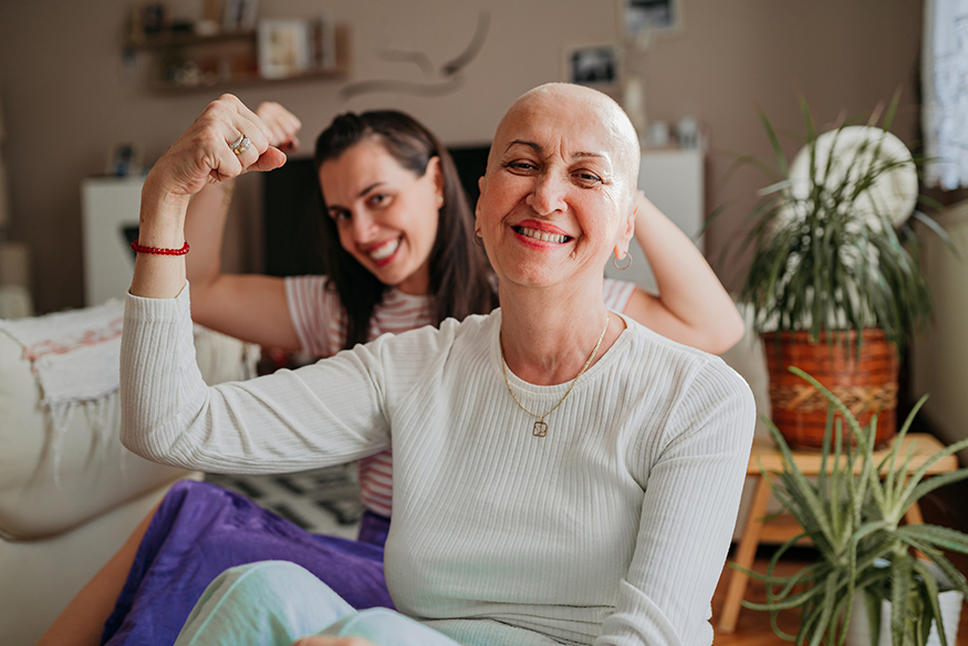 Two bald women flexing their right arm muscles