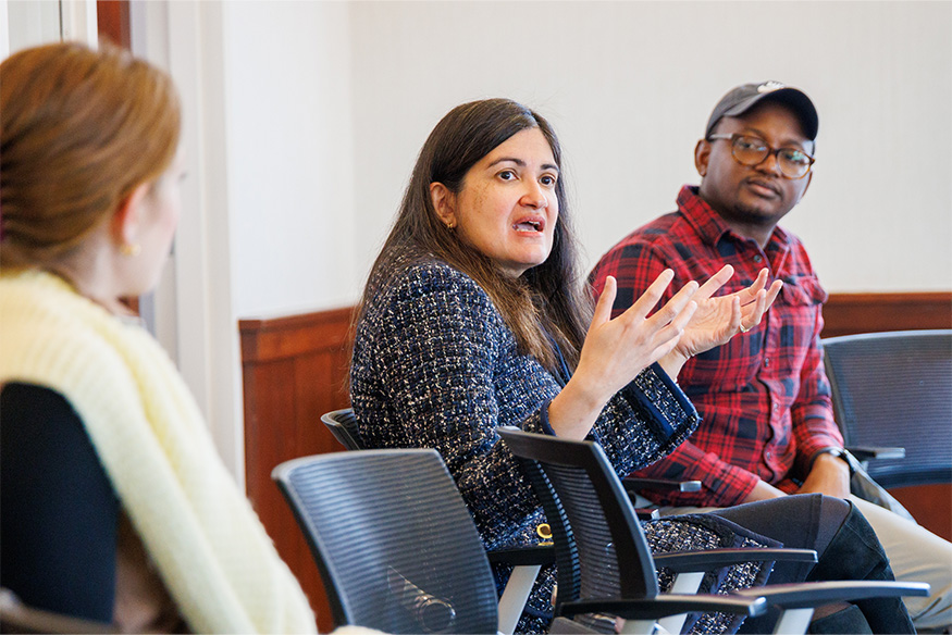Woman talking and sitting while two people sit beside her and watch