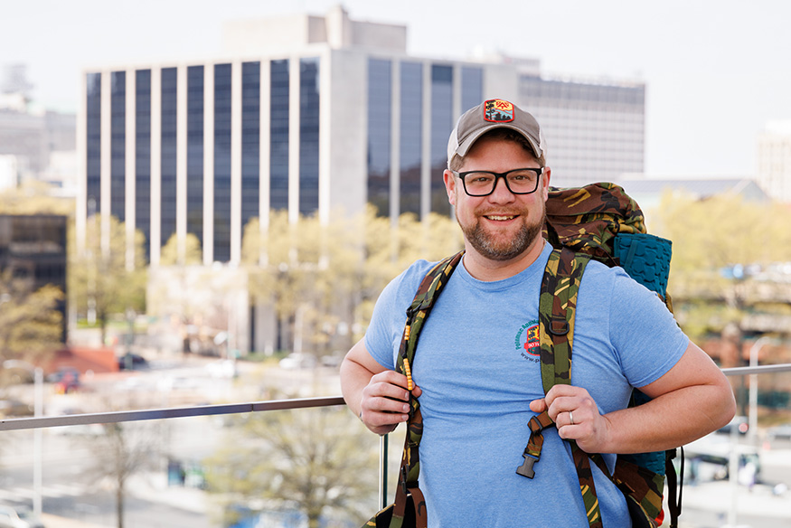 VCU Massey social media manager Keith Jones poses wearing search and rescue gear, outside on VCU Health's campus