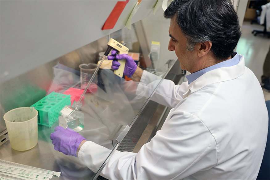 Man using medical device wearing a white medical coat and purple gloves