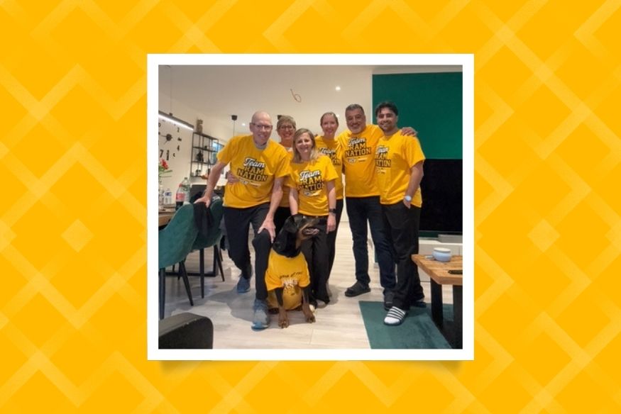 Six people smiling and wearing matching bright yellow 