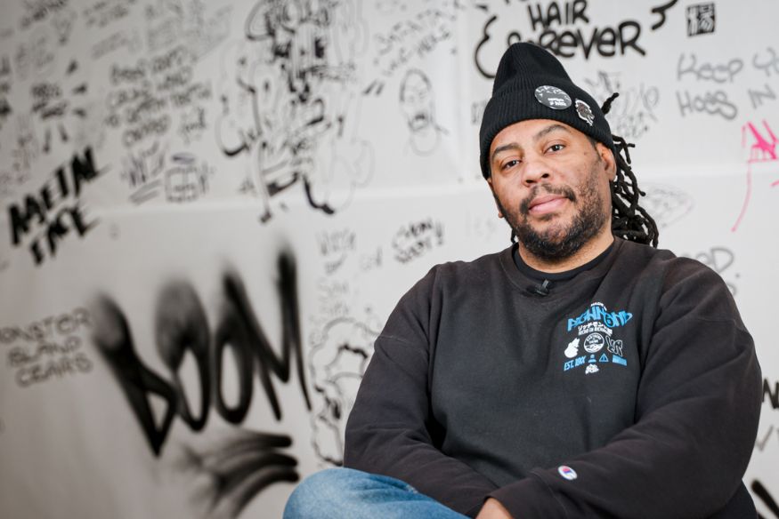 Man sitting in chair with art mural behind him