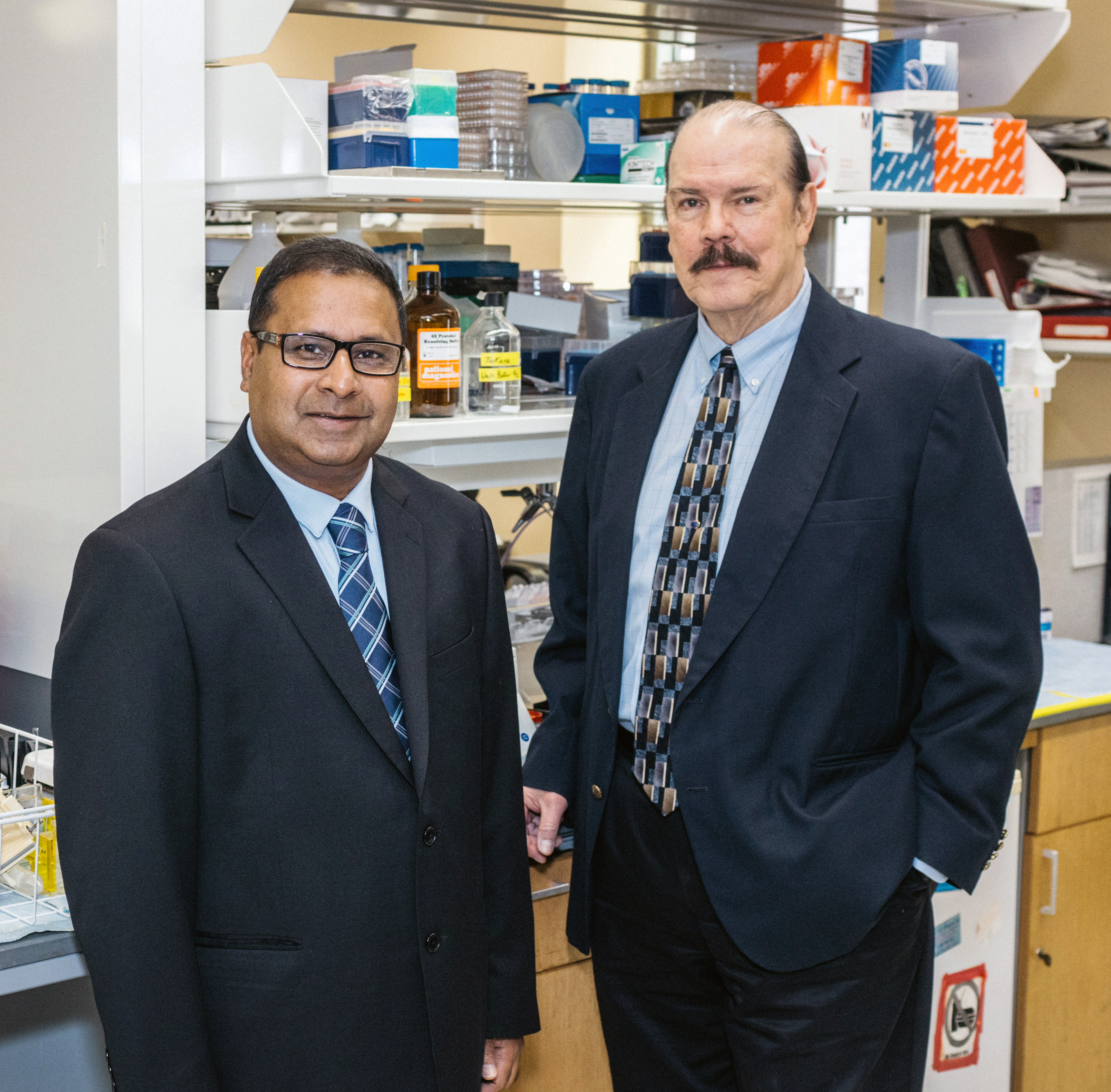 Two men in buisness suits standing next to each in a medical lab