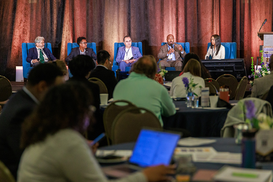 Wide shot of a panel discussion with onlooking crowd