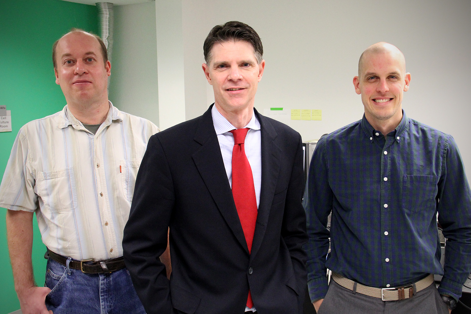 Three physicists posing in a lab