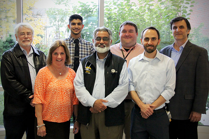 Dr. Amir Toor standing with a group of research collaborators